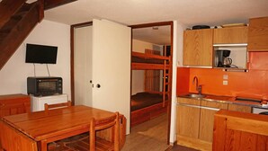 A compact kitchen with wooden cabinets, a microwave, and a sink. - Studio 6 Personnes Accès Direct aux Pistes (LES ORRES 1650)