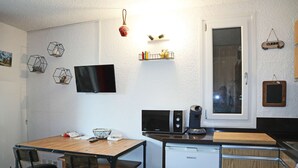 A compact kitchen with a wooden table and chairs, a built-in microwave, a coffee maker, and a dishwasher. - Studio 6 Personnes Accès Direct aux Pistes (LES ORRES 1650)