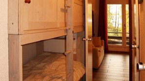 A bunk bed room with a wooden floor, a door leading to a balcony, and a wall-mounted light fixture. - Studio 6 Personnes Accès Direct aux Pistes (LES ORRES 1650)