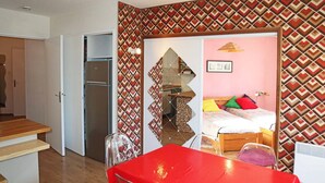 Una habitación compacta con cama, una mesita pequeña y kitchenette.