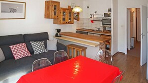 Un espacio habitable compacto con kitchenette, zona de comedor y sofá con cojines estampados.