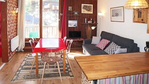 Un salón acogedor con una mesa de madera, un sofá y un televisor.