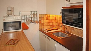 Kompakti keittiö, jossa on kahvinkeitin, mikroaaltouuni, pesuallas ja liesi.