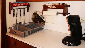 Une cuisine avec des meubles de rangement en bois, une machine à café, un panier et une boîte de mouchoirs.