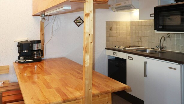 Una cocina compacta con encimera de madera, cafetera, microondas y lavavajillas.