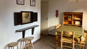 A dining area with a wooden table and chairs, a bench, and a wall-mounted shelf with kitchen utensils.