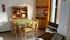 A dining area with a wooden table and chairs, a wooden cabinet with glass doors, and a small wooden chest of drawers.
