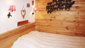 A bedroom with a wooden headboard, a white bedspread, a nightstand, and wall-mounted lamps.