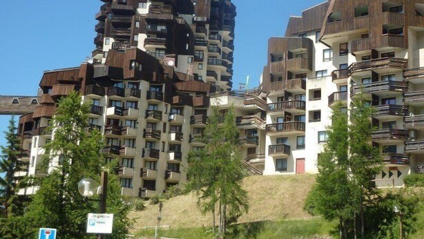 A multi-story residential building with balconies and a parking sign in the foreground.