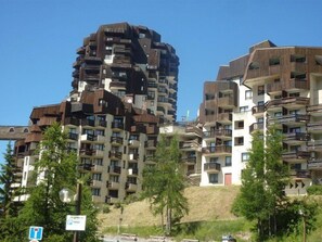 Um edifício residencial de vários andares, com varandas e um sinal de estacionamento em primeiro plano.