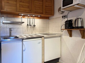 Een koelkast, kookgerei, borden en bestek