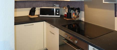 Een koelkast, een oven, een vaatwasser, kookgerei, borden en bestek