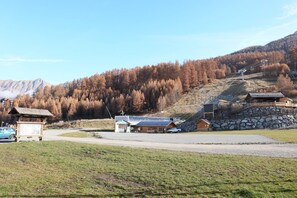 A mountain lodge with a stone wall, wooden cabins, and a ski lift in the background.