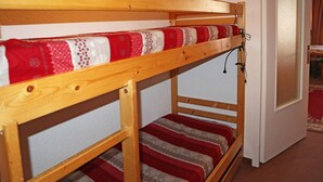 A bunk bed with a red and white patterned bedspread, a wooden frame, and a door with a frosted glass panel. - Studio 4 Personnes vue Pistes (LES ORRES 1650)