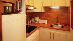 A compact kitchen with a dishwasher, a coffee maker, a toaster, and a sink. - Appartement N° 101 LE Belvedere (LES ORRES 1650)