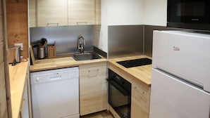 A compact kitchen with a dishwasher, oven, and a built-in microwave.