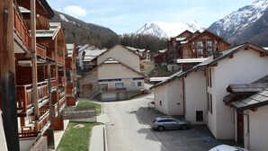 A mountain village with wooden buildings, a restaurant, and a car parked on the street. - Appartement Parc DES Airelles 211 (LES ORRES 1800)