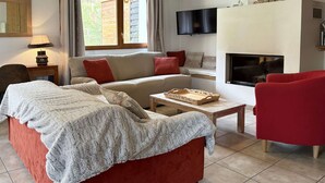 Un salon chaleureux avec un canapé rouge, une table basse en bois et une cheminée.