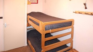 A bunk bed with a wooden frame and a mattress. - Grand Studio 4 Personnes (LES ORRES 1650)