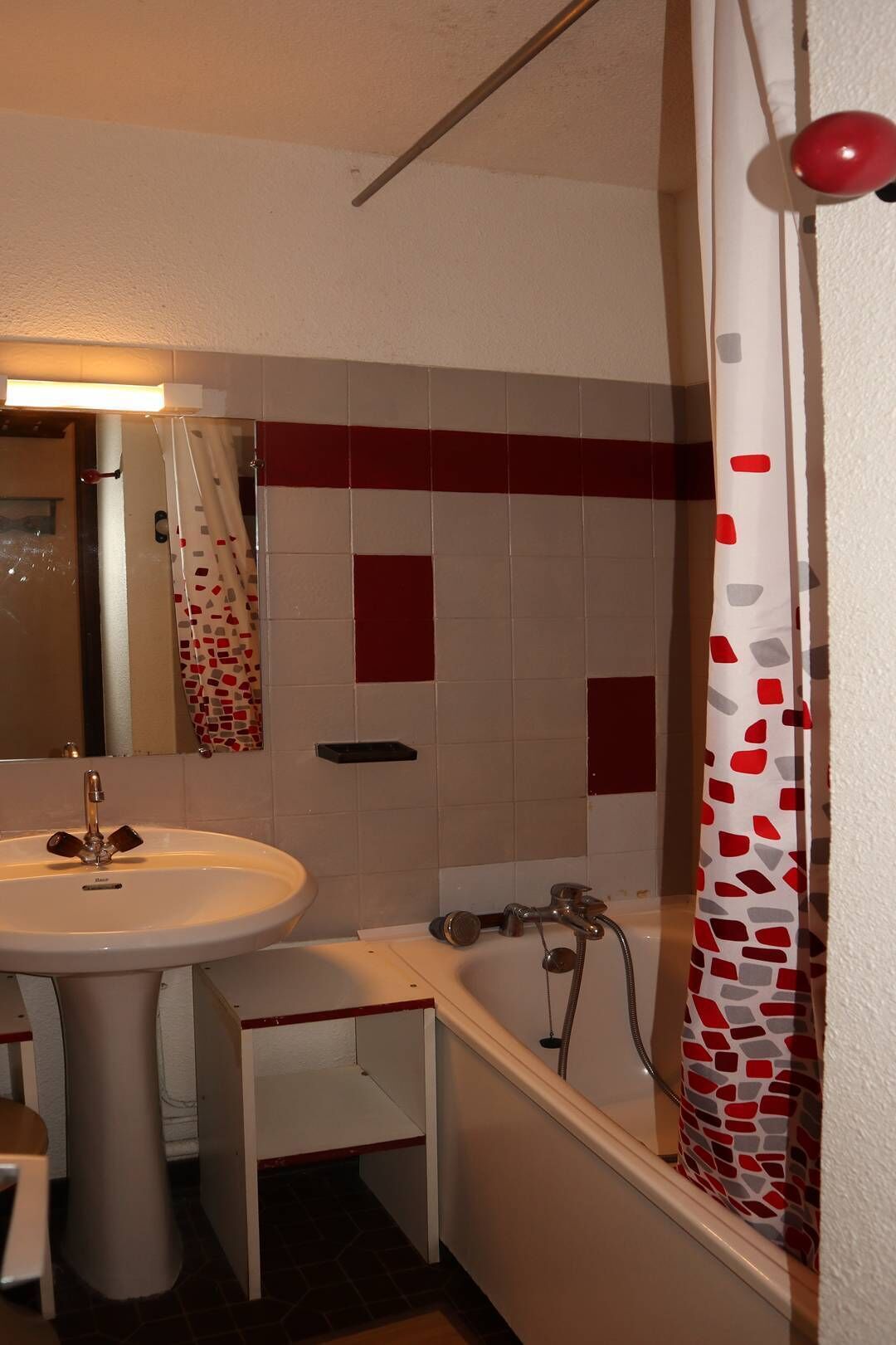A bathroom with a sink, mirror, shower curtain, and tiled walls.
