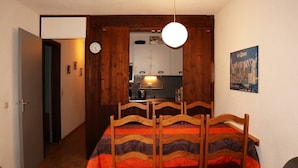 Ein Essbereich mit Holztisch und -stühlen, einer Wanduhr und einem Poster von Les Orres.