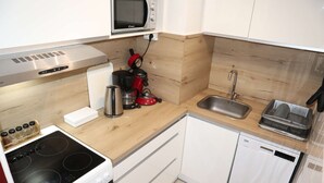 A compact kitchen with a stove, microwave, sink, and dishwasher.