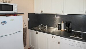 A compact kitchen with white cabinets, a black countertop, a microwave, a sink, a coffee maker, and a dishwasher. - Studio N° 213 LES Flocons (LES ORRES 1650)