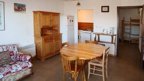 A compact living space with a kitchenette, a dining table with chairs, a sofa, and a bunk bed. - Appartement G307 LES Cembros (LES ORRES 1650)