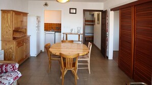 A compact kitchen with a dining table, wooden cabinets, and a built-in oven. - Appartement G307 LES Cembros (LES ORRES 1650)