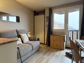 Una sala de estar acogedora con un sofá, un aparador de madera y un comedor con mesa y sillas.
