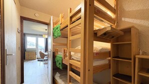 A room with bunk beds, a desk, and a chair.