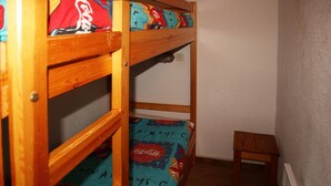 A bunk bed with colorful bedding and a small wooden stool. - Studio 6 Personnes Accès Direct aux Pistes (LES ORRES 1650)
