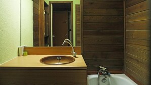 A bathroom with a wooden vanity, a sink, a mirror, and a bathtub.