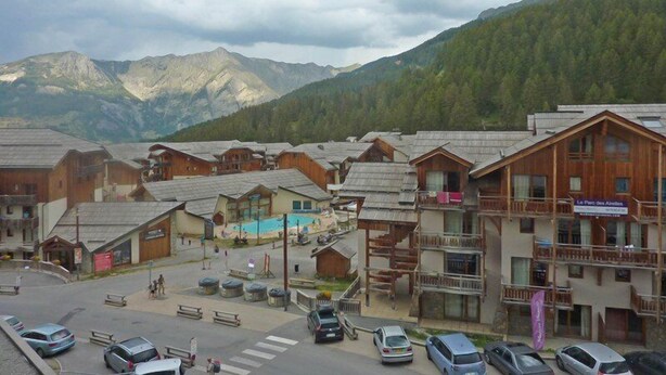 Un complejo turístico de montaña con edificios de madera, una piscina y vistas a las montañas.