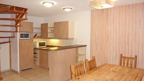Una cocina compacta con microondas, armarios de madera y un comedor con mesa y sillas de madera.