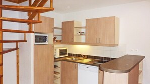 Una cocina compacta con armarios de madera, microondas, lavavajillas y una pequeña encimera.