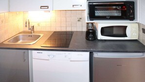 A compact kitchen with a sink, a microwave, a coffee maker, and a dishwasher.