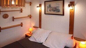 A bedroom with a bed, two bedside tables, a clock, and wall-mounted lights.