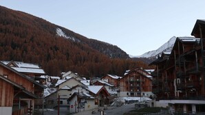 Un borgo montano con edifici in legno e una montagna innevata sullo sfondo.