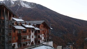 Un edificio in legno a più piani con balconi, sullo sfondo di montagne.