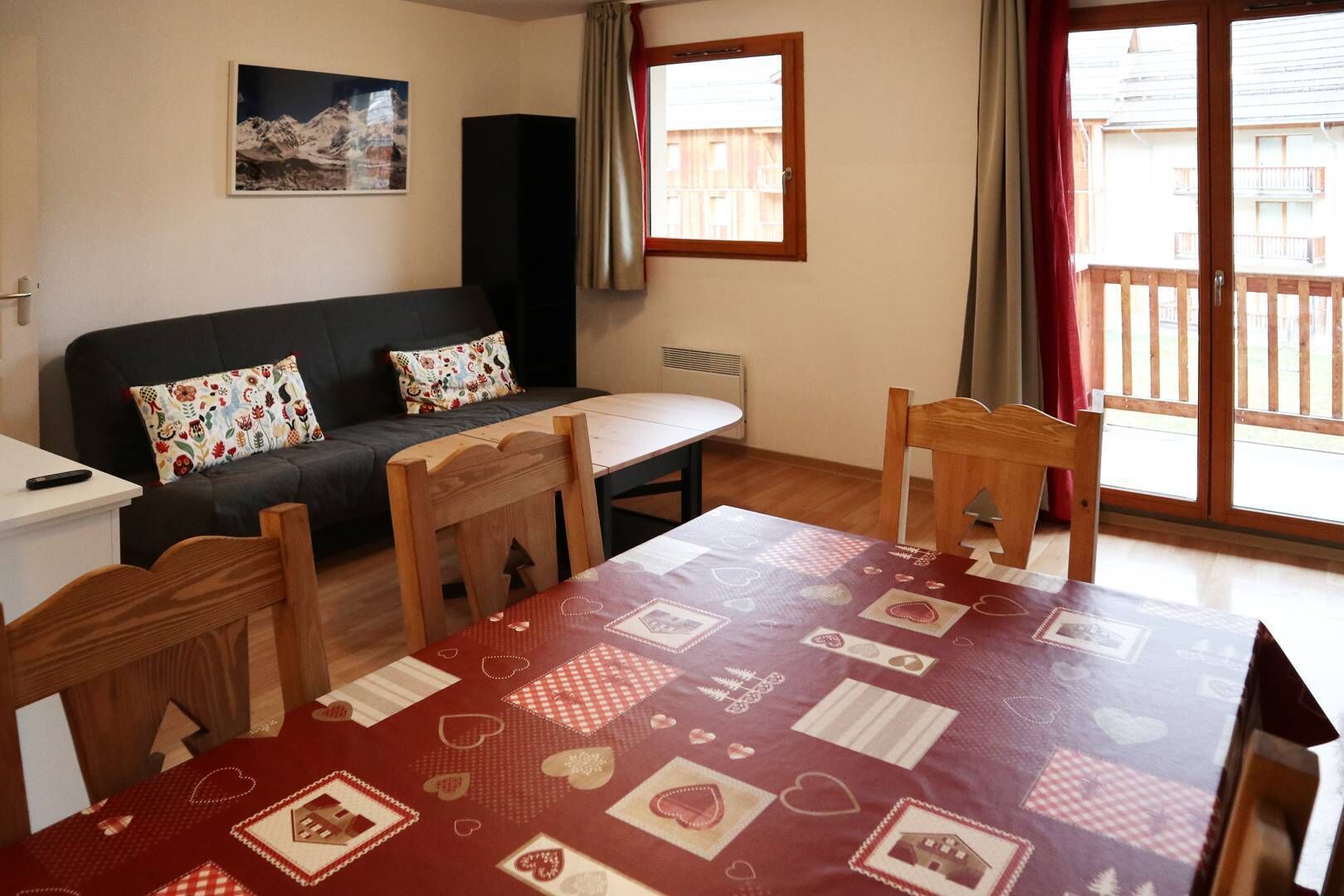 A cozy room with a sofa, a dining table, and a window with a view of buildings.