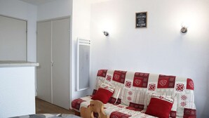 A cozy room with a sofa adorned with a red and white quilt, a wooden chair, and a small table.