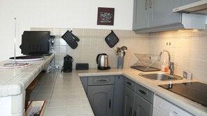 A modern kitchen with grey cabinets, a stainless steel sink, and a coffee machine.