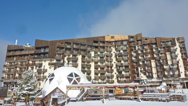 A multi-story hotel with balconies, a central dome structure, and outdoor seating areas.