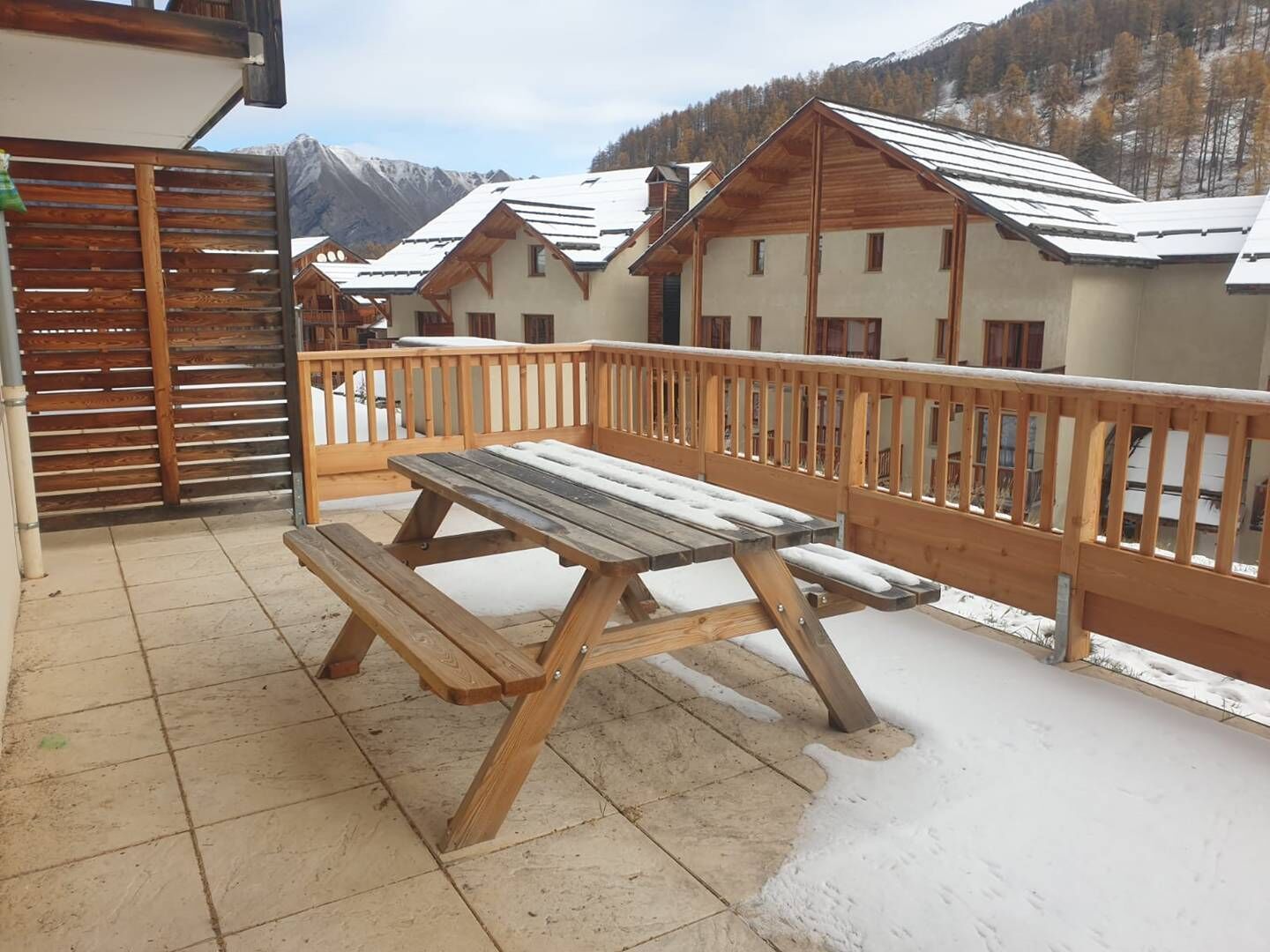 A wooden deck with a picnic table and a wooden fence.