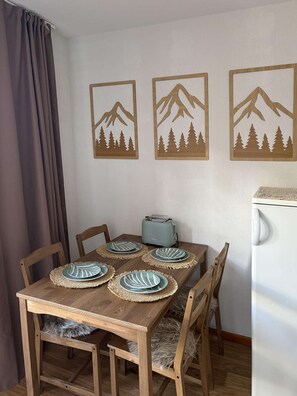 A dining area with a wooden table, four chairs, and three wooden wall art pieces depicting mountains and trees.