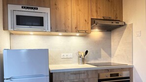 A compact kitchen with a built-in microwave, oven, and refrigerator.