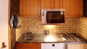 Une cuisine dotée de meubles en bois, d’un four à micro-ondes, d’un lave-vaisselle Bosch et d’un évier en acier inoxydable.