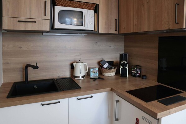 A modern kitchen with a built-in microwave, a kettle, a coffee maker, and a wine rack.