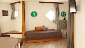 Een slaapkamer met een bed, een klein tafeltje, een stoel, een raam en een radiator.